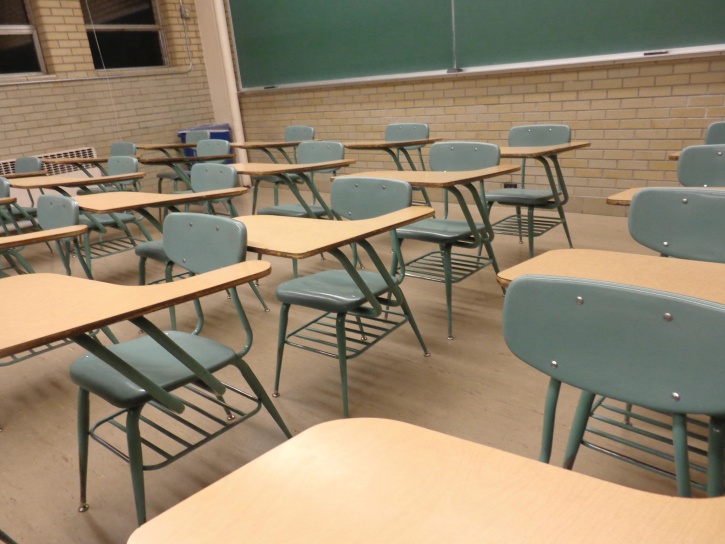 A Classroom With Desks Chairs And Bulletin Board On The Wall That Says