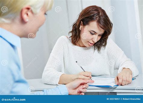 A Doctor Is Filling Out Paperwork At A Desk In A Office Stock Image