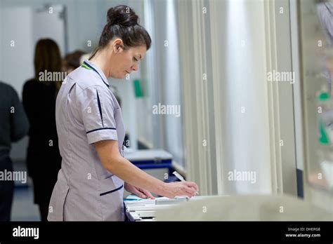 A Nurse Fills Out Some Paperwork In An Nhs Reception Uk Stock Photo Alamy