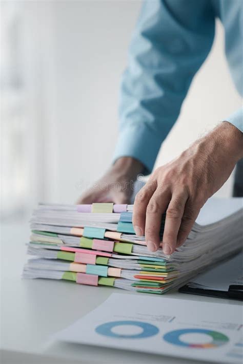 A Person In An Office With A Huge Stack Of Papers He Is A Company