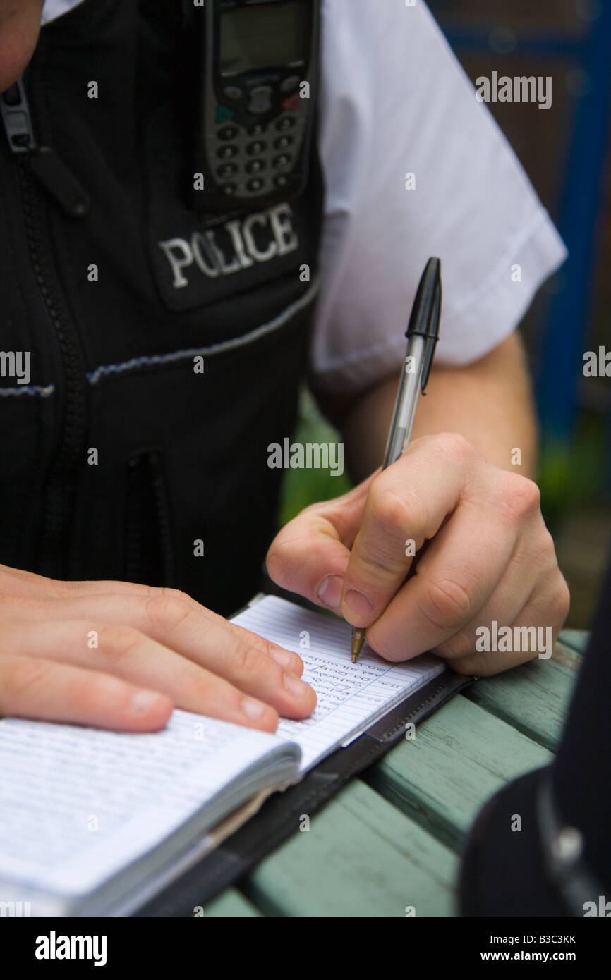 A Police Officer Fills Out His Pocket Note Book With Evidence Stock