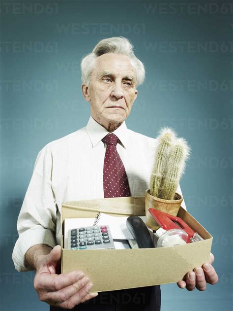 A Senior Man Carrying A Box Of Possessions After Being Fired Stock Photo