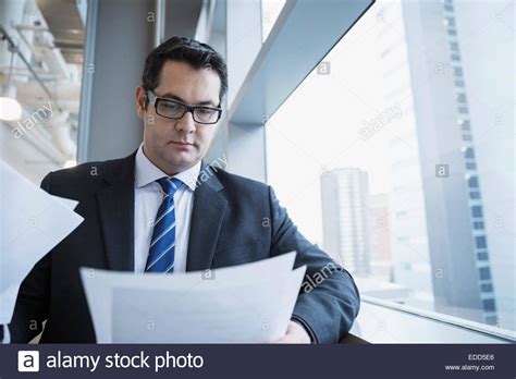 Businessman Reading Paperwork At Office Window Stock Photo Alamy