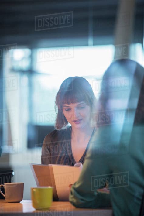 Businesswomen Reading Paperwork In Office Stock Photo Dissolve