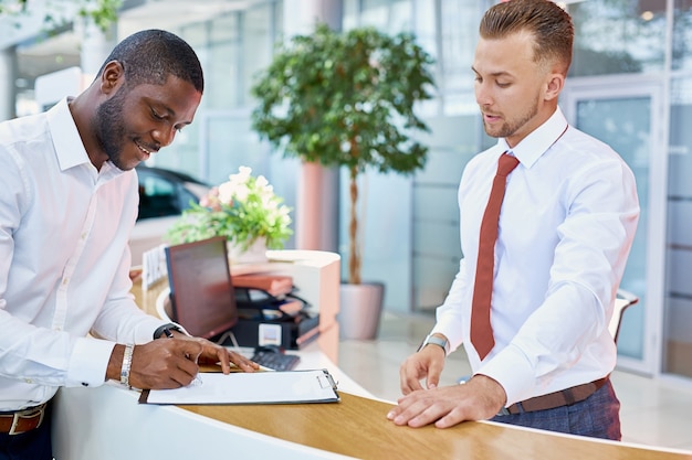 Car Buyers African Clients Signing Papers With Salesman In Dealership Store Stock Image Image