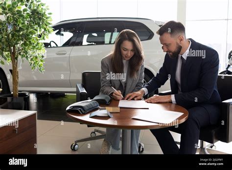 Car Dealership Employee Helps Fill Out New Car Purchase Paperwork Stock