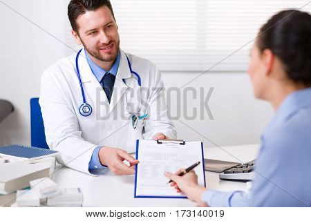 Close Up Of Female Patient Sign Paperwork In Hospital Stock Image