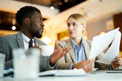 Confident Interracial Business Partners Doing Paperwork Together While