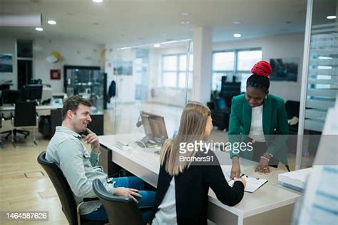 Couple Buying A New Car Signing Paperwork At Car Showroom High Res