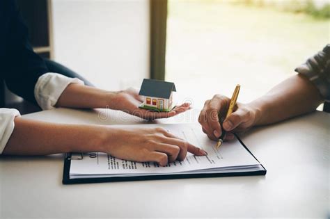 Customer Signing A Paper Document For Buying House Estate Agent Stock