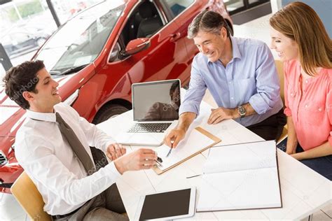 Customers Signing Documents At Car Showroom Stock Photo