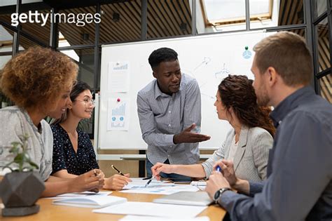 Diverse Colleagues Busy Brainstorming Discussing Paperwork At Briefing