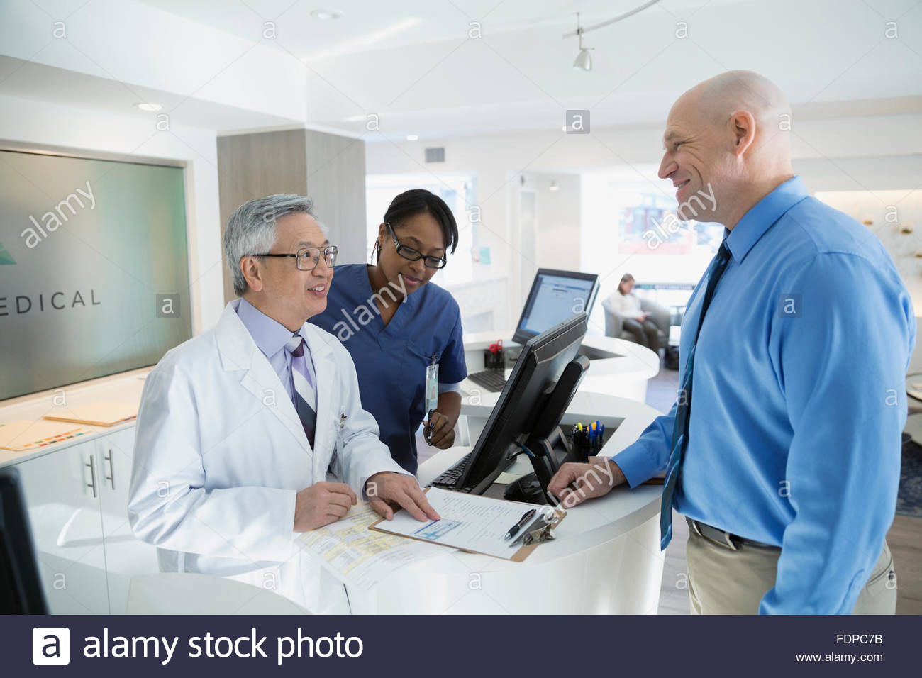 Doctor Discussing Paperwork With Patient In Clinic Stock Photo Alamy