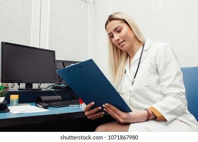 Doctor In The Office Checking Paperwork And Patient S Medical Records