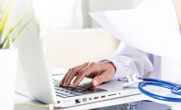 Doctor Typing Information Of Patient Prescription From Paperwork