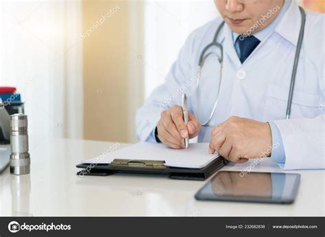 Doctor Writing On Medical Health Care Record Patients Discharge Or