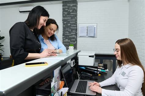 Female Doctor And Patient Filling Out And Signing Forms Standing At