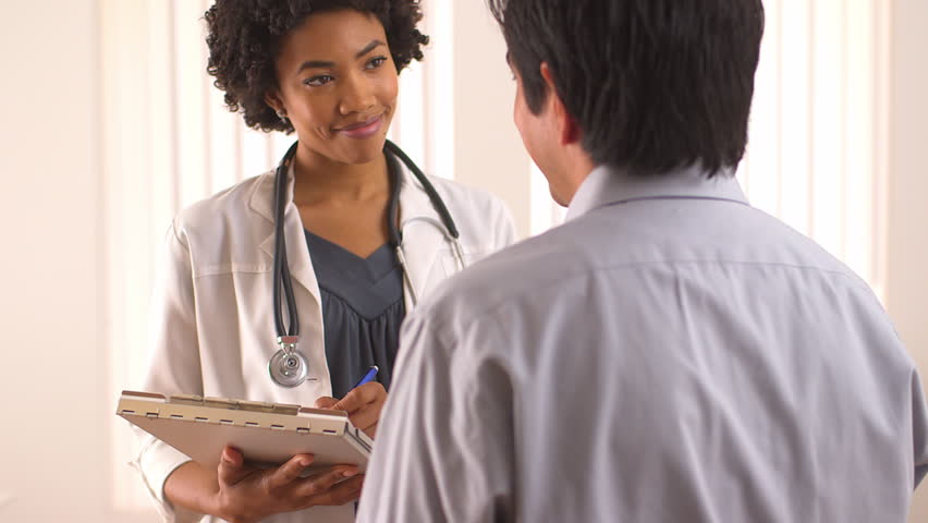 Female Patient Filling Out Medical Document With Doctor Stock Photo