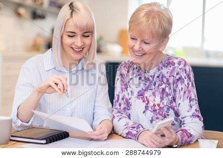 Financial Advisor Helping Senior Neighbor With Paperwork Stock Photo