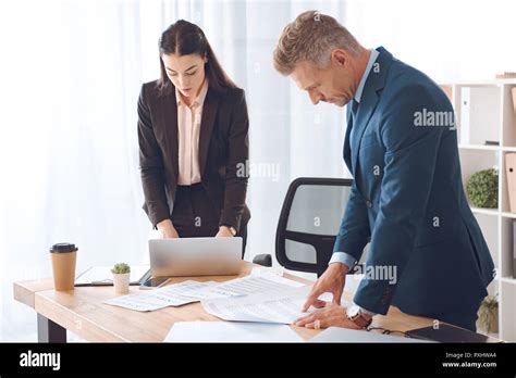 Focused Business Colleagues Doing Paperwork At Workplace In Office