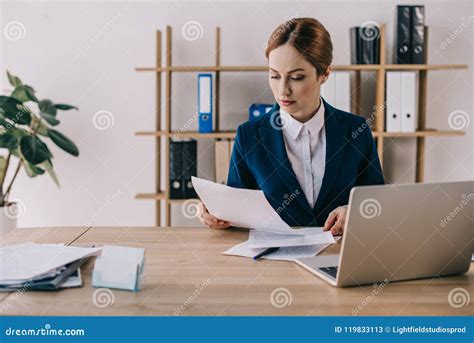 Focused Businesswoman In Suit Doing Paperwork At Workplace In Office