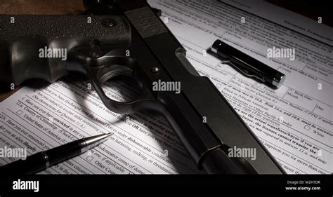 Gun And Pen On Firearm Purchase Paperwork With Dishonorable Discharge Question Highlighted Stock