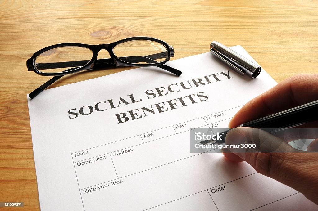 Hand Filling Out Social Security Benefits Paperwork Stock Photo