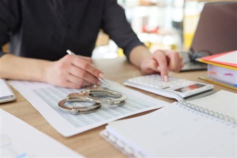 Handcuffs On Investigation Paper While Worker Making Counts Stock Photo