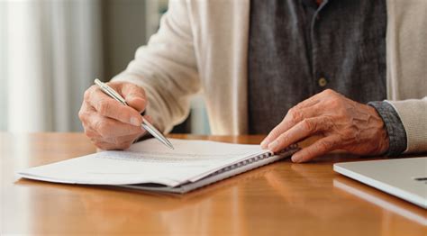 Hands Of Pension Man Reading Retirement Paperwork About Policy