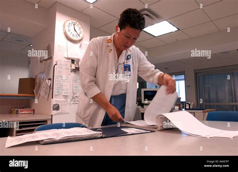 Hospital Nurse Looking Over Patient Paperwork With Medical Equipment In