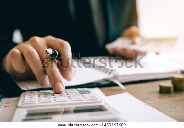 Investors Calculating On Calculator Investment Costs Stock Photo