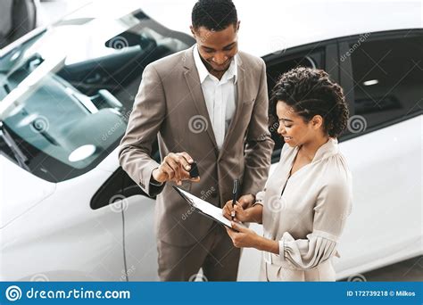 Lady Buying Car Signing Papers With Dealer In Dealership Store Stock