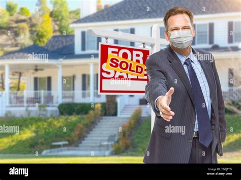 Male Real Estate Agent Reaching For Hand Shake Wearing Medical Face Mask With Sold For Sale Sign