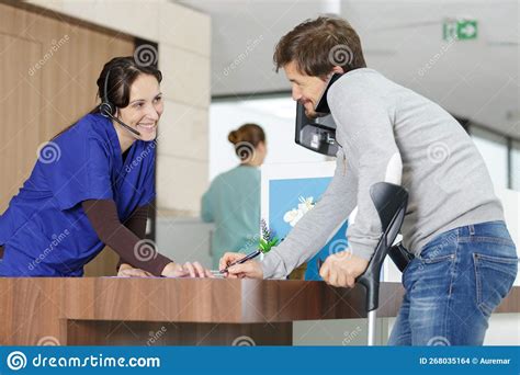 Man On Crutches Signing In At Hospital Reception Stock Photo Image Of Doctor Explaining