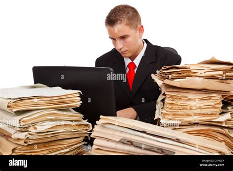 Man Working On Laptop Computer Surrounded With Lots Of Paperwork Stock