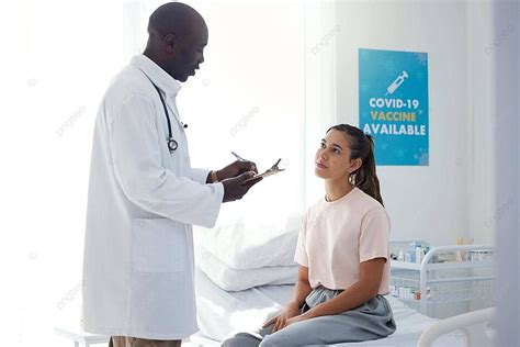 Medical Team Consulting And Diagnosing Patient While Healthcare Worker Handles Paperwork Photo