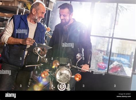 Motorcycle Mechanic Discussing Paperwork With Customer In Shop Stock Photo Alamy