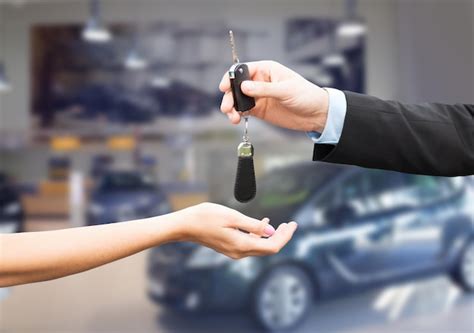 People And Ownership Concept Close Up Of Car Salesman Giving Key To