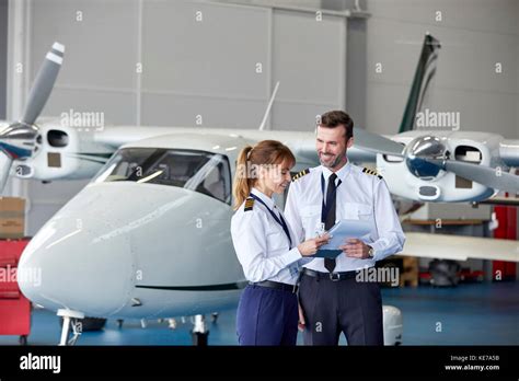 Pilots Discussing Paperwork Near Airplane In Hangar Stock Photo Alamy