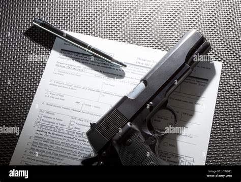 Pistol And Pen On The Required Paperwork For A Gun Purchase Stock Photo