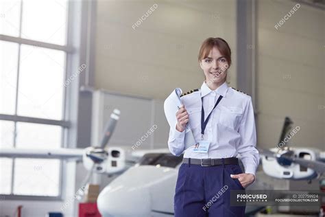 Portrait Confident Pilot With Paperwork In Airplane Hangar Three