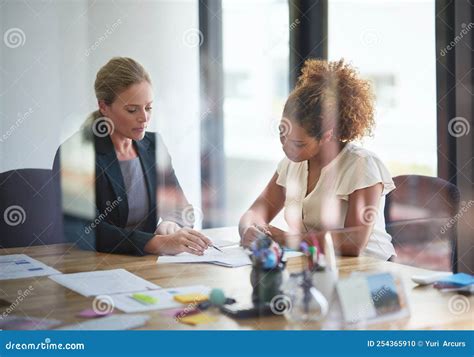 Putting Paperwork In Order Two Businesswoman Sitting In An Office Discussing Paperwork Stock