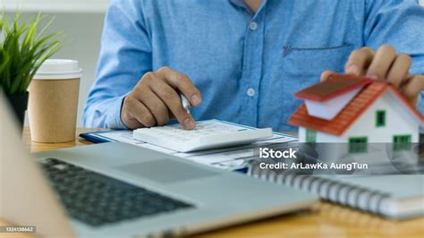 Real Estate Agents Work At Desks In Rooms With Paperwork And House