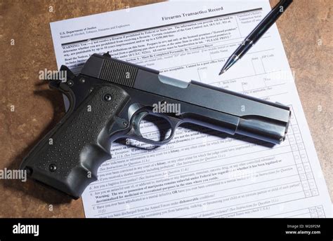 Semi Automatic 1911 Handgun And Pen With Purchase Paperwork On A Tan