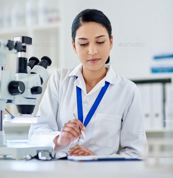 Shot Of A Young Woman Filling Out Paperwork While Working A Laboratory