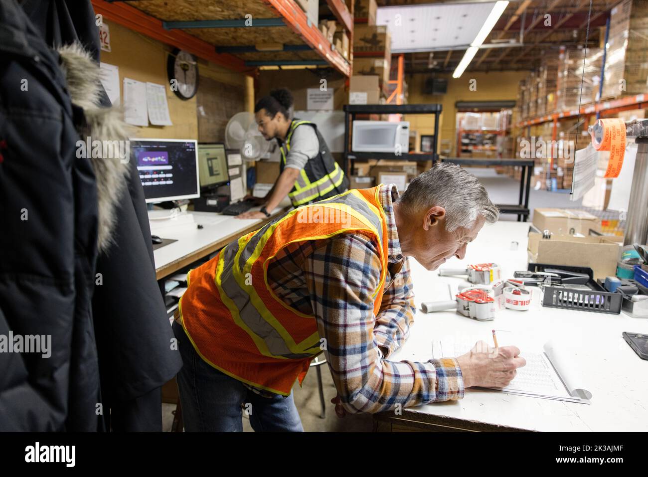 Worker Leaning On Table Checking Paperwork In Distribution Warehouse