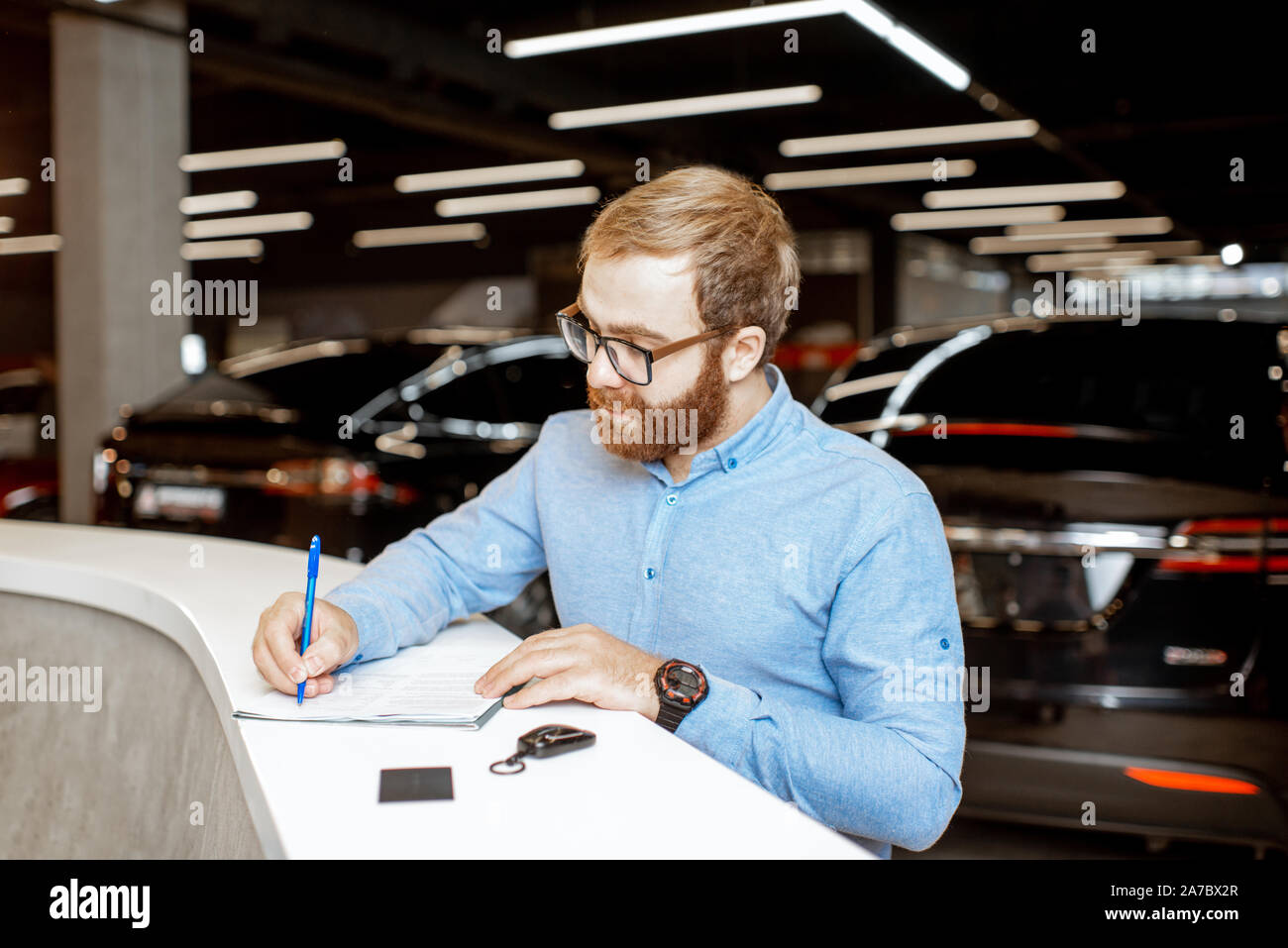 Young Man Signing Some Documents Buying Or Renting A Car In The Modern