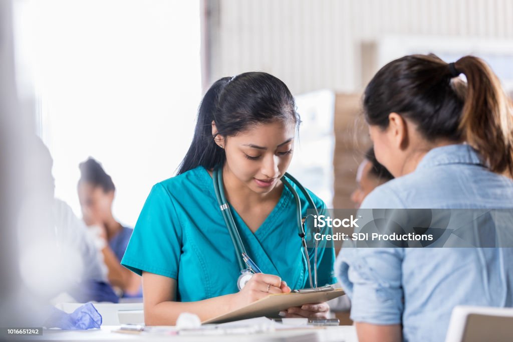 Young Nurse Fills Out Intake Paperwork For New Patient Stock Photo